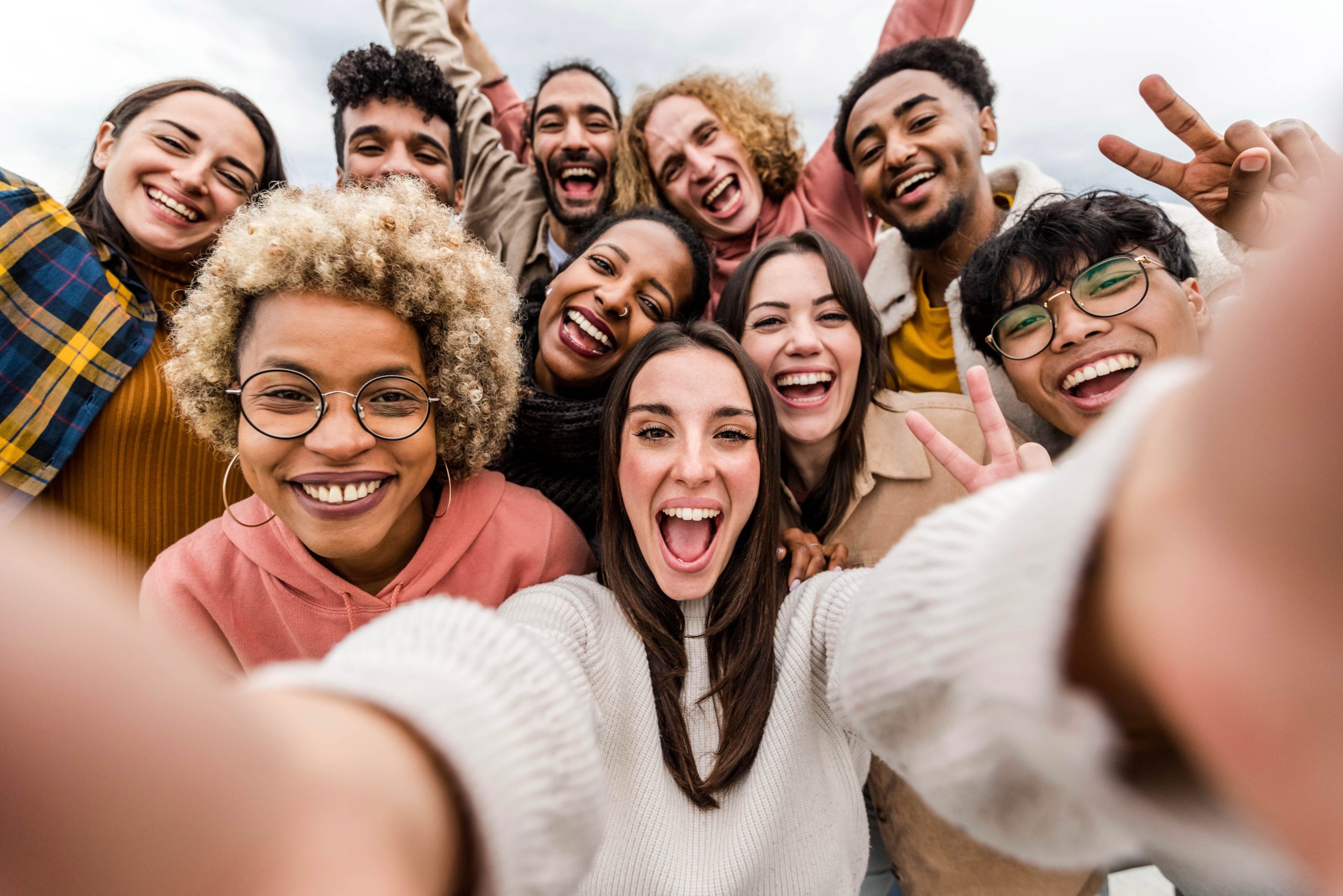 Multiracial friends taking big group selfie shot smiling at came