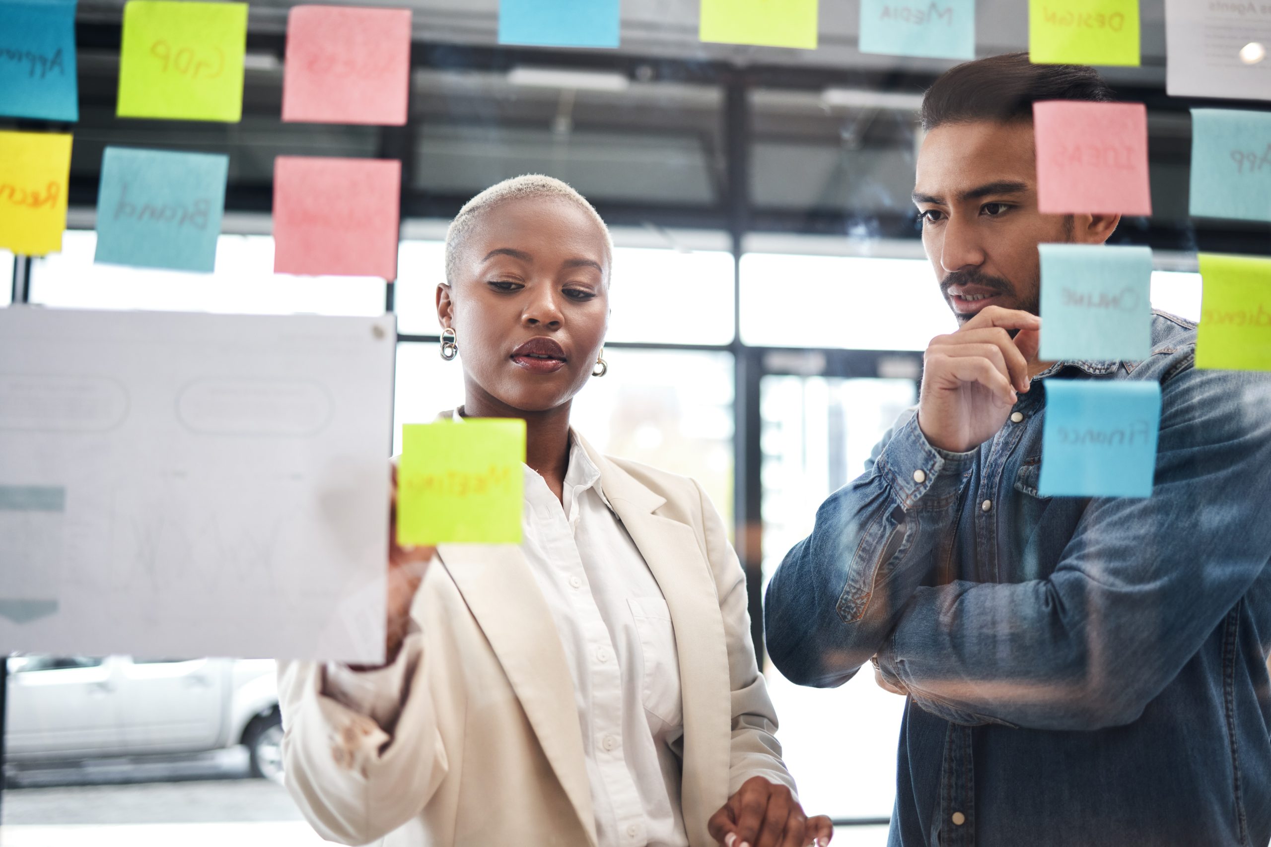 Creative people, team and thinking in planning for schedule brainstorming or meeting at office. Man and woman in teamwork decision for project plan, tasks or sticky note ideas in startup at workplace